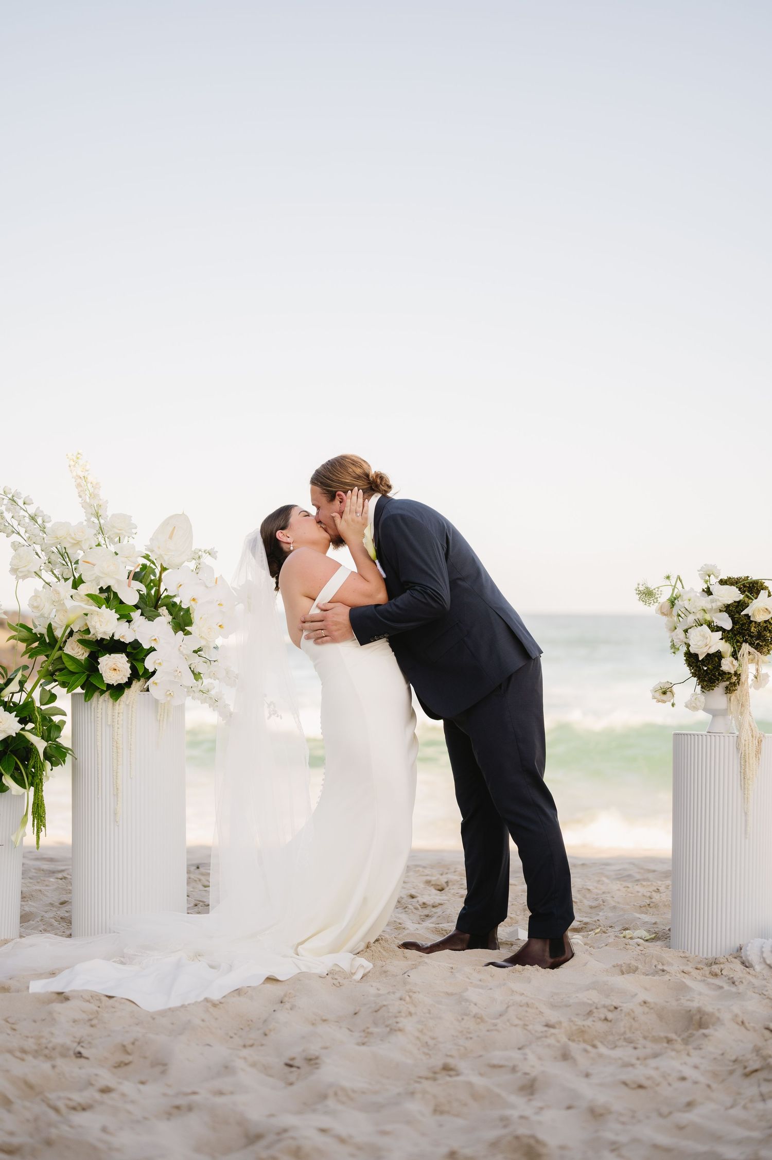 A joyful beach wedding ceremony with guests throwing confetti as the newlyweds celebrate on the sand.