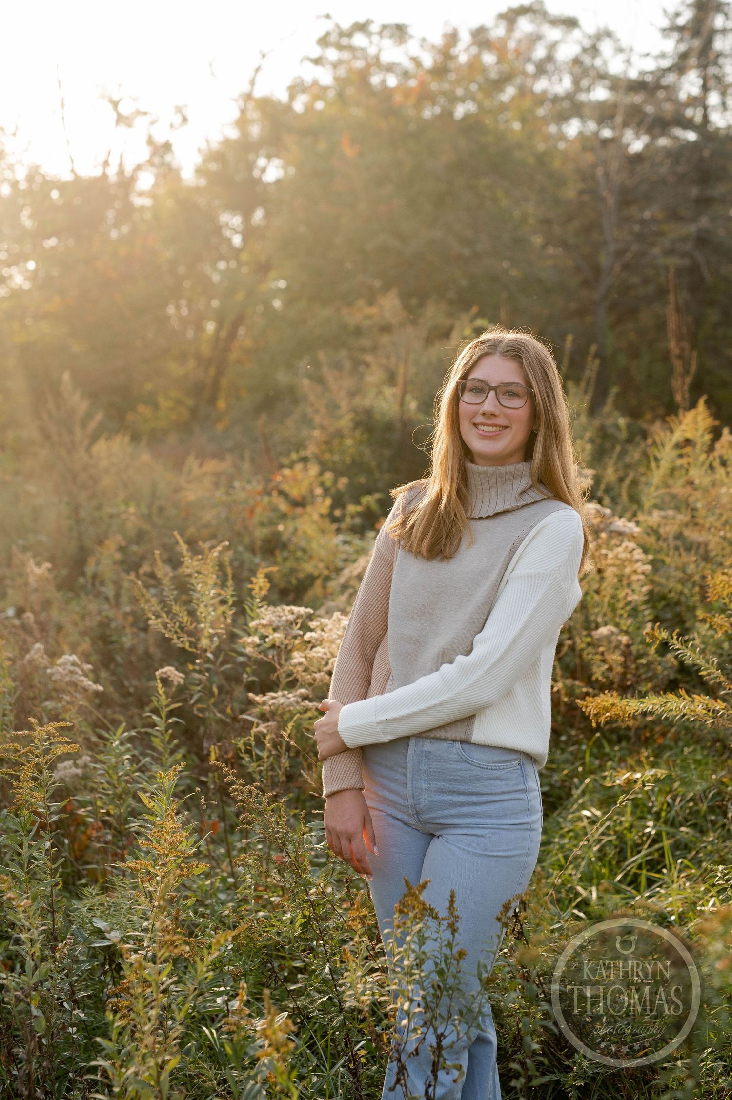 Soft sunset lighting creates a warm glow around a person in a turtleneck sweater outdoors.
