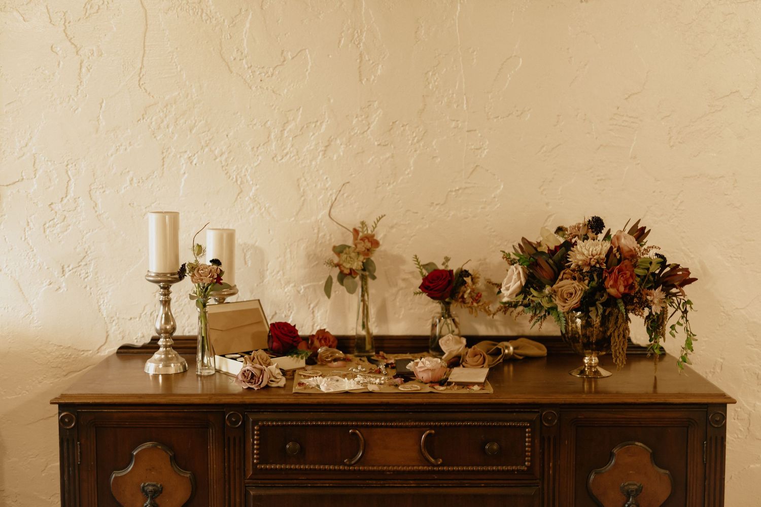 Vintage wooden sideboard decorated with candles, flowers and decor items for an elegant event.