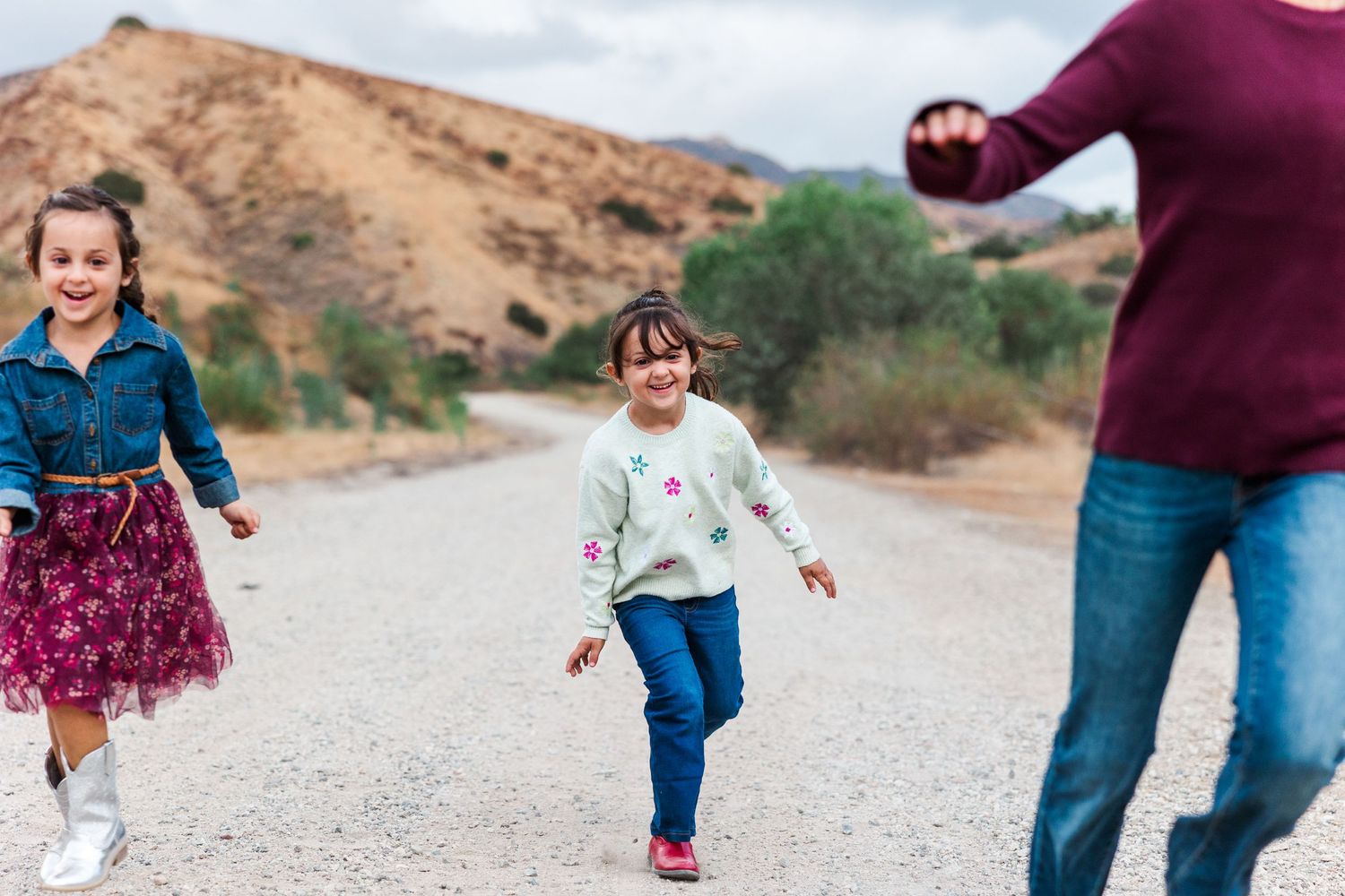 Children running playfully on a gravel path with Simi Valley hills in the background.