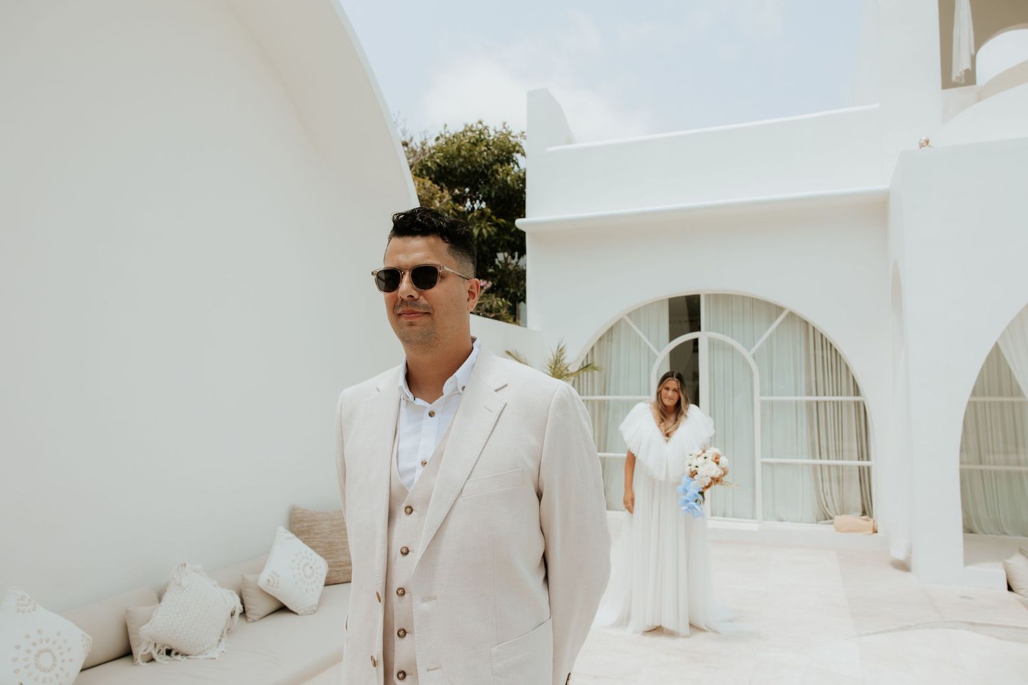 Elegant Mediterranean-style courtyard with white arched architecture and decorative palm trees.