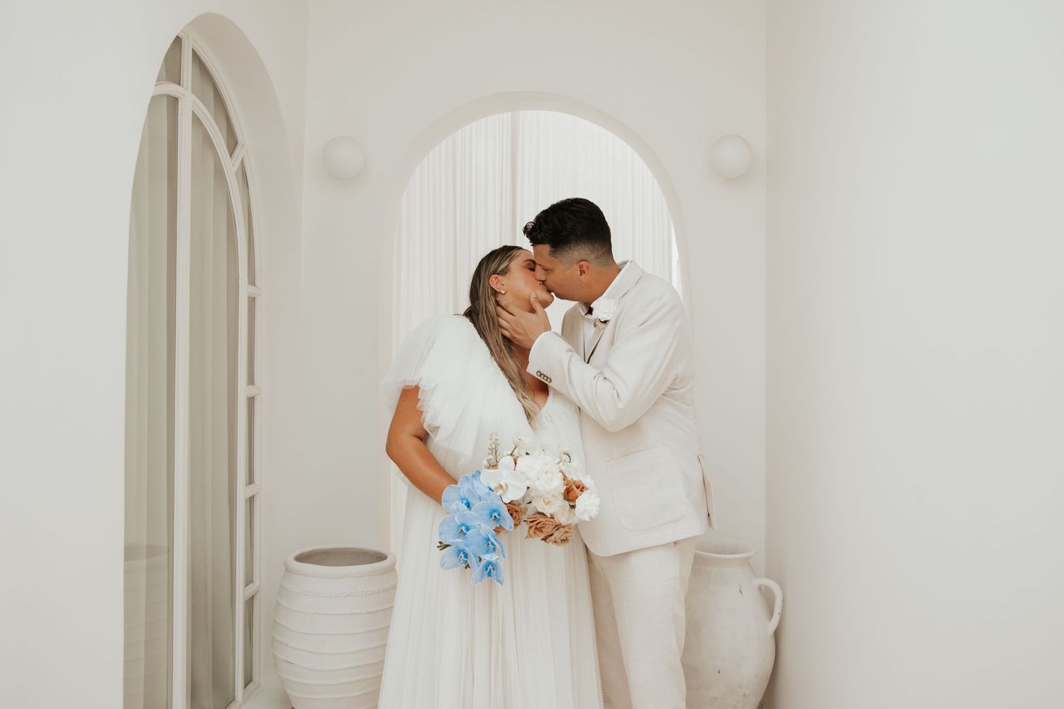 An intimate wedding moment captured under a white arched doorway.