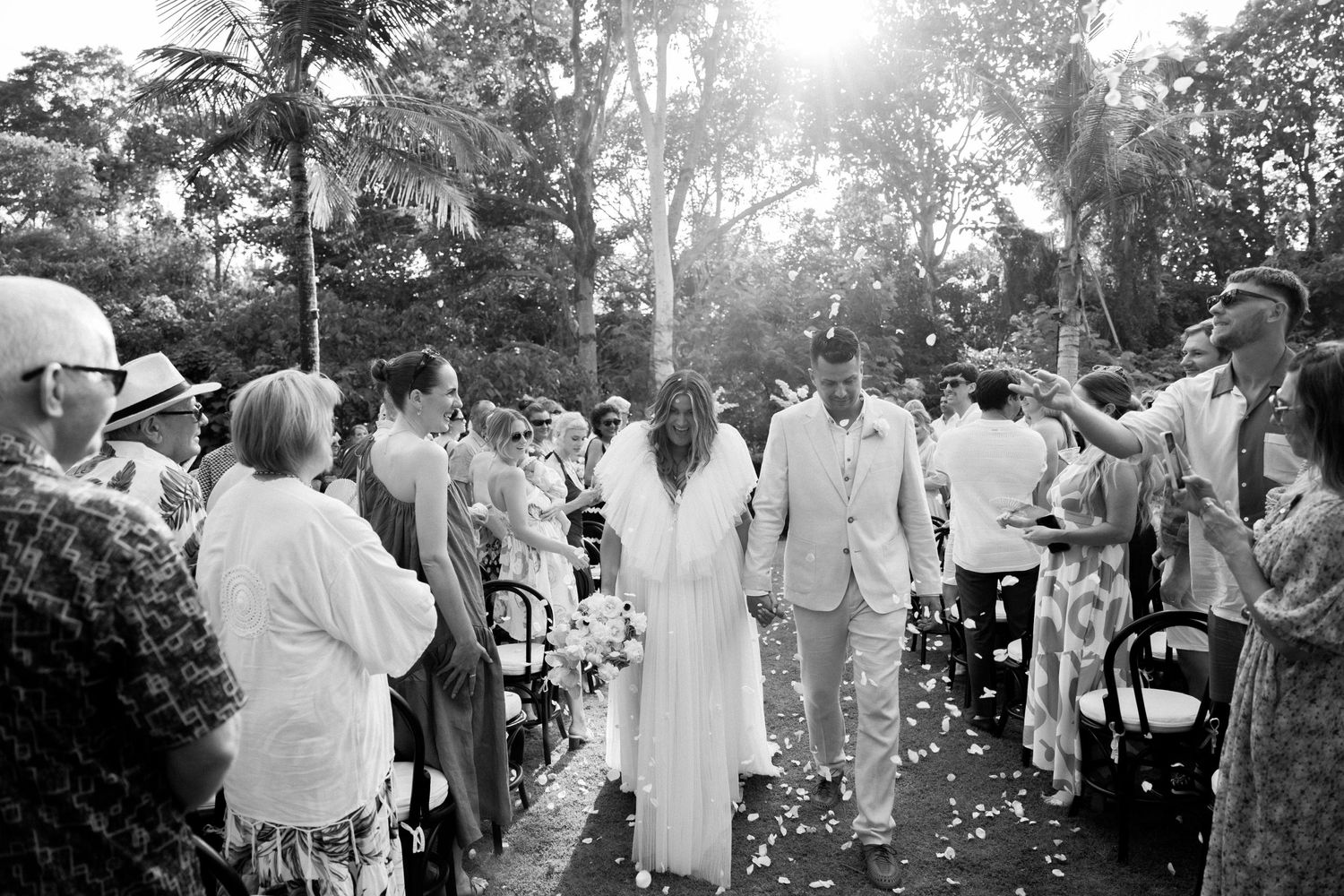 Wedding guests shower the couple with flower petals during the ceremony recessional.