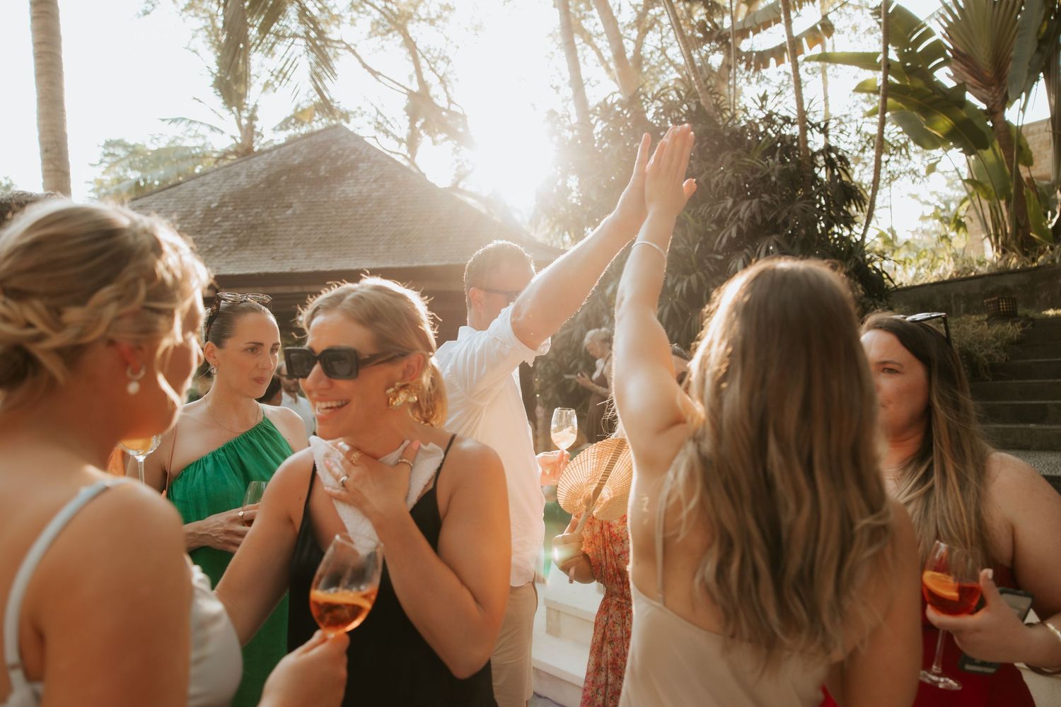 Wedding celebration with guests dancing and cheering during golden hour.