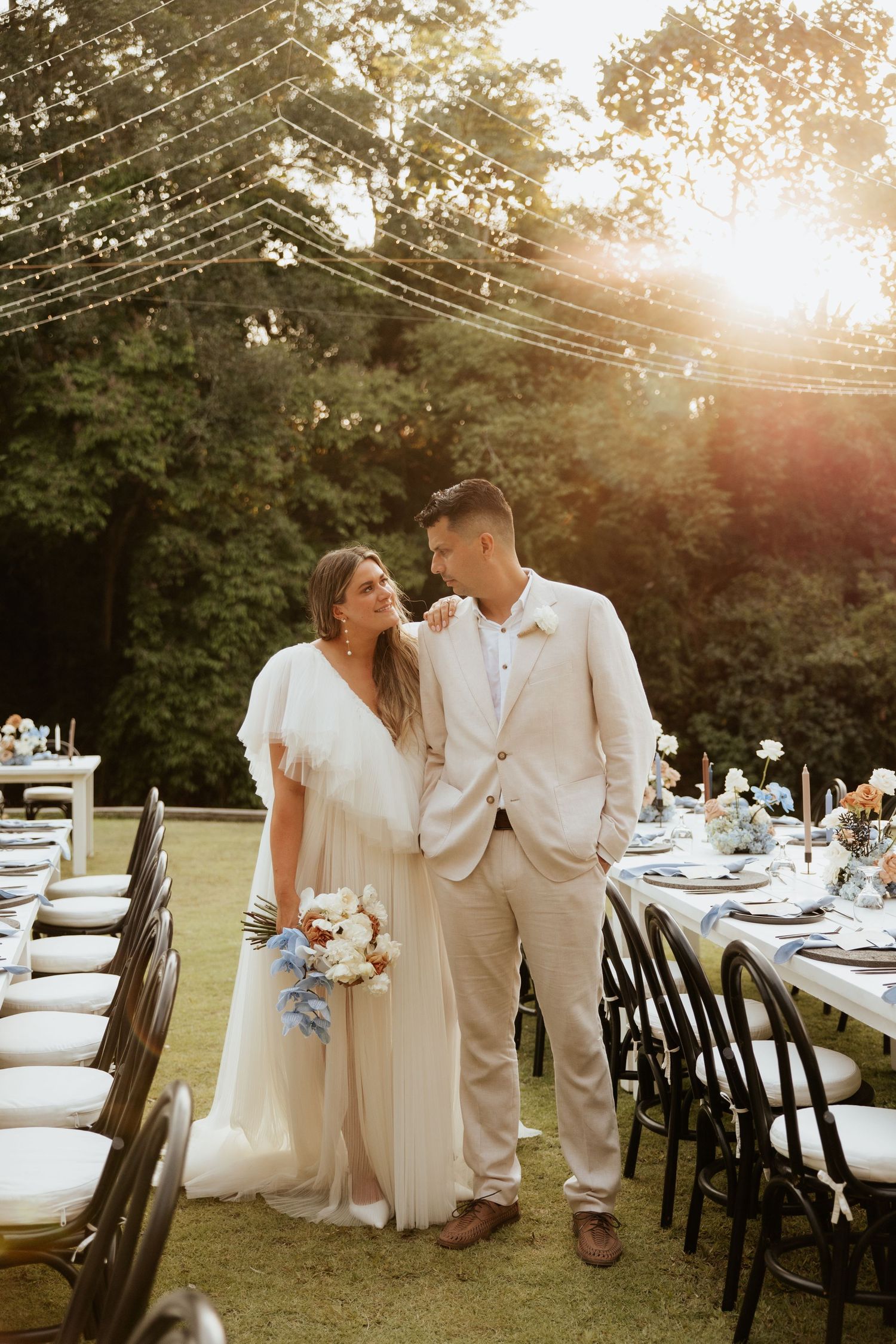 A romantic sunset wedding reception setup with string lights and elegant table settings.