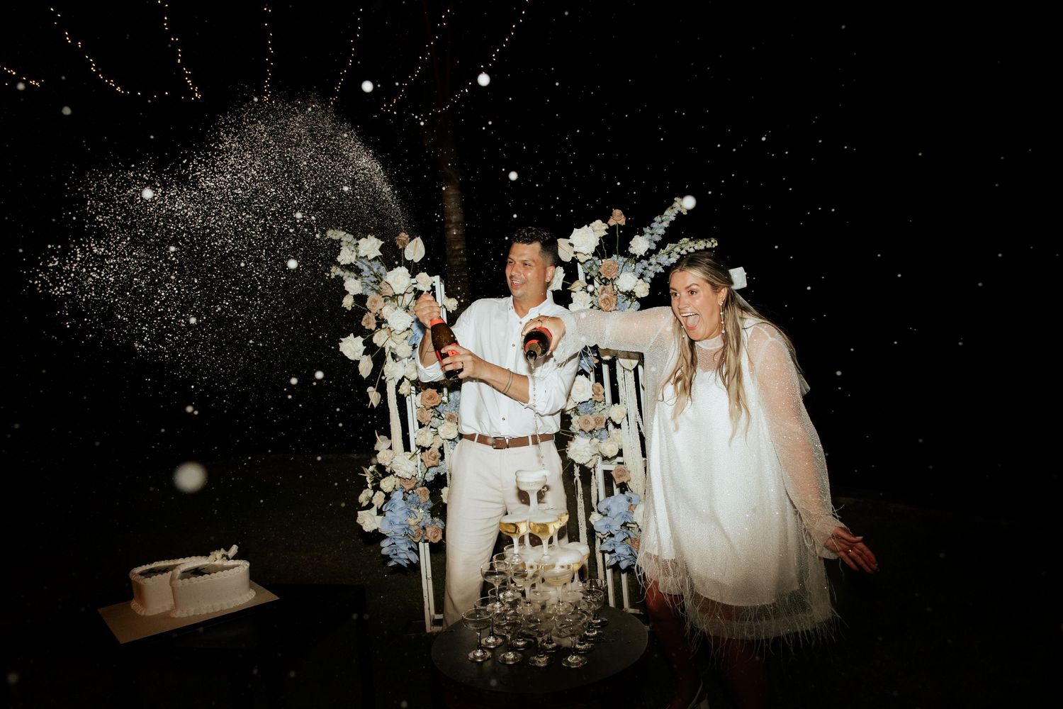 A celebratory moment captured with sparklers and floral decorations at a nighttime wedding celebration.