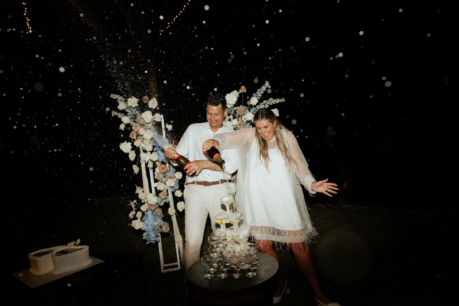 Couple celebrating at nighttime wedding reception with sparkle lighting and decorative display.