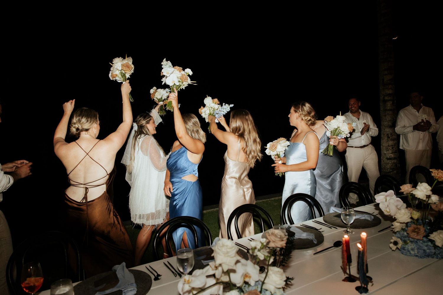 Wedding guests holding bouquets dance and celebrate during the evening reception.