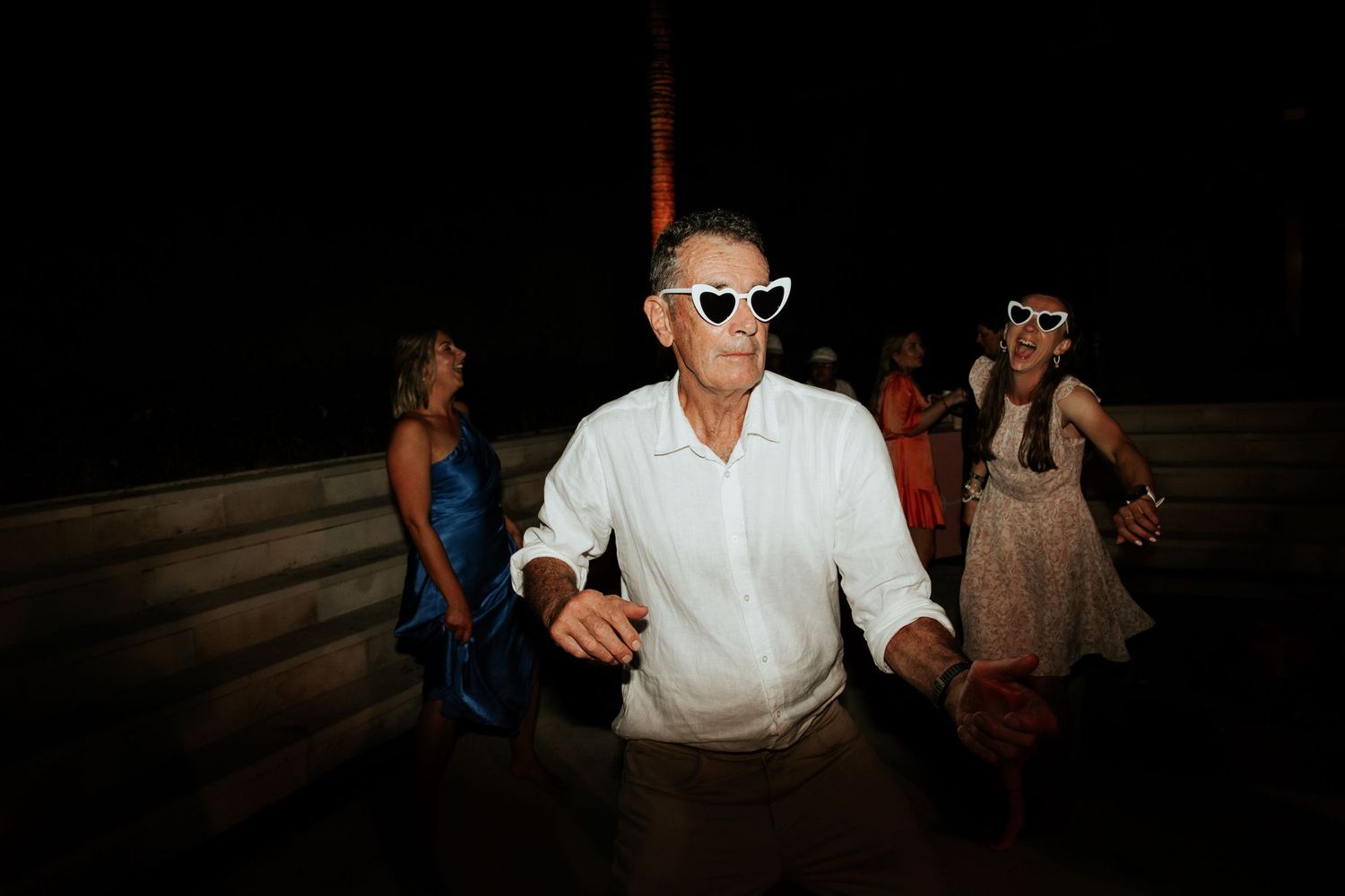 Guest in sunglasses enjoying the dance floor at a nighttime wedding reception.