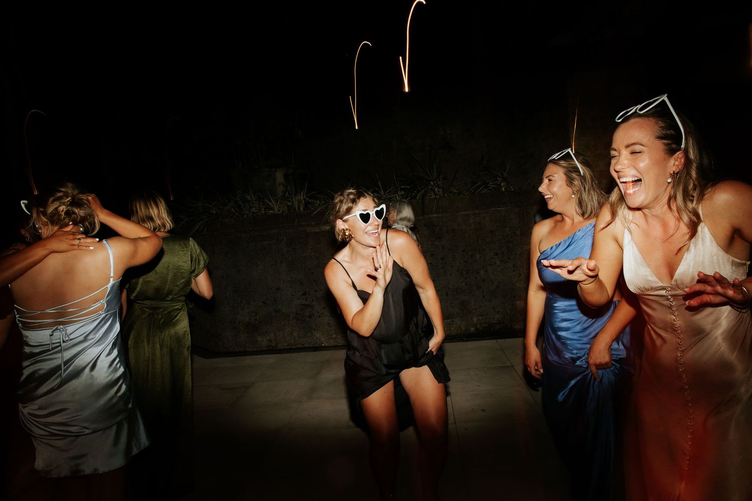 Party-goers dancing and having fun at a nighttime celebration event with vibrant flash photography capturing the energy.