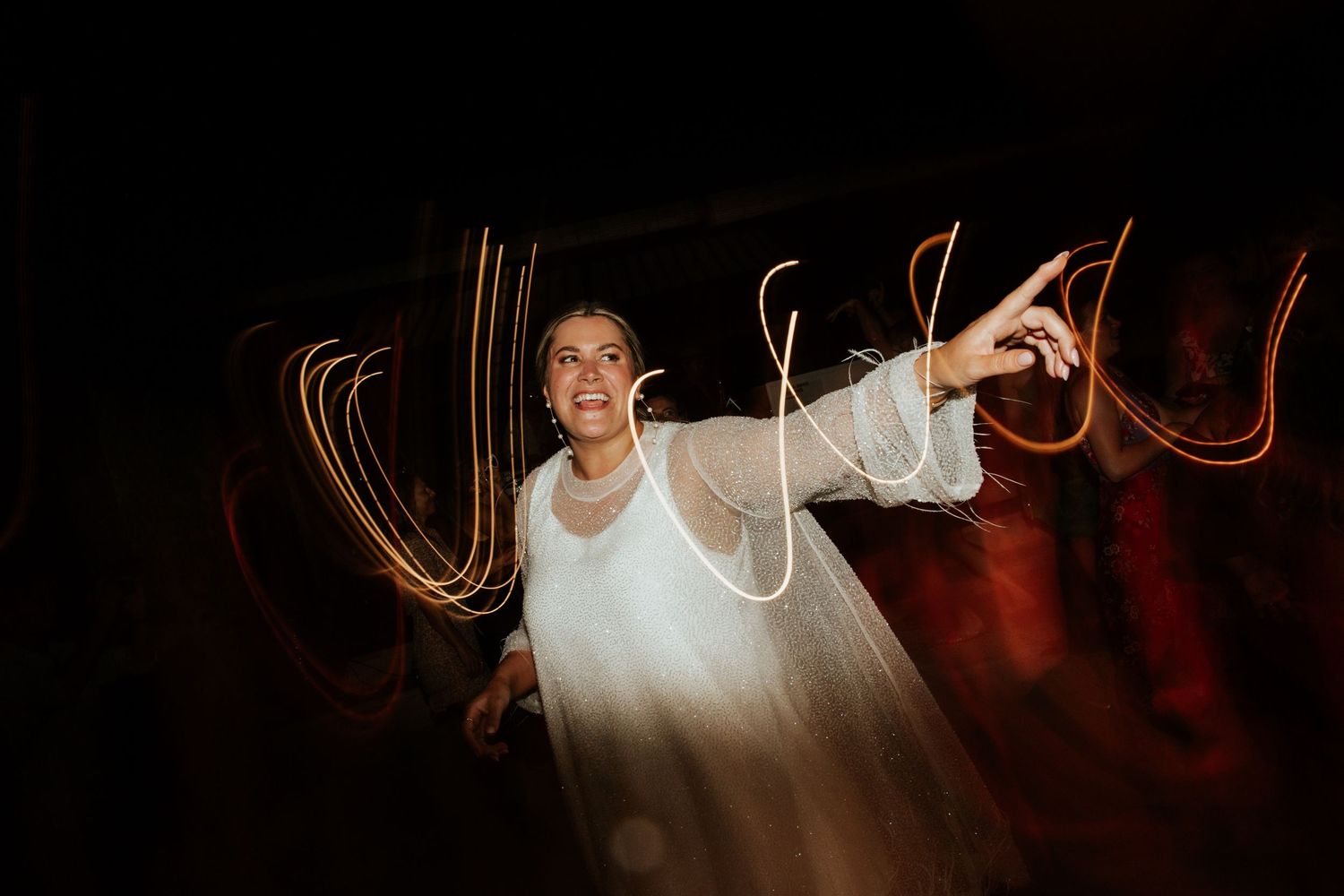 Long exposure night photograph captures light painting streaks of orange and red around someone in white clothing.