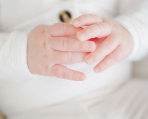 Sweet newborn moment — close view of baby hands resting together, soft and serene