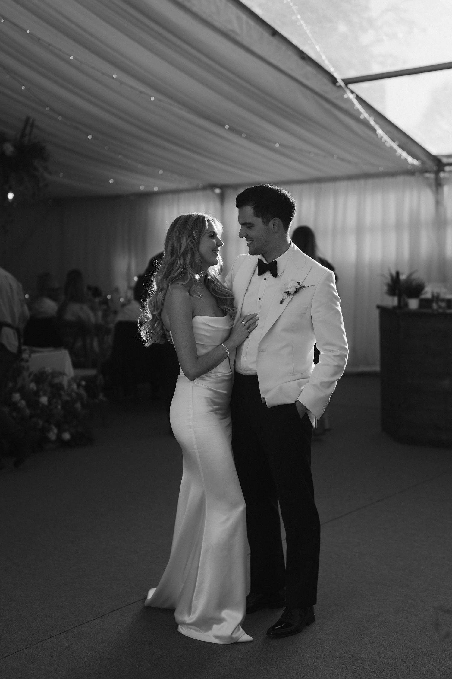 bride and groom smiling at each other, backlit by the sun coming through the marquee roof at hamswell house wedding in bath