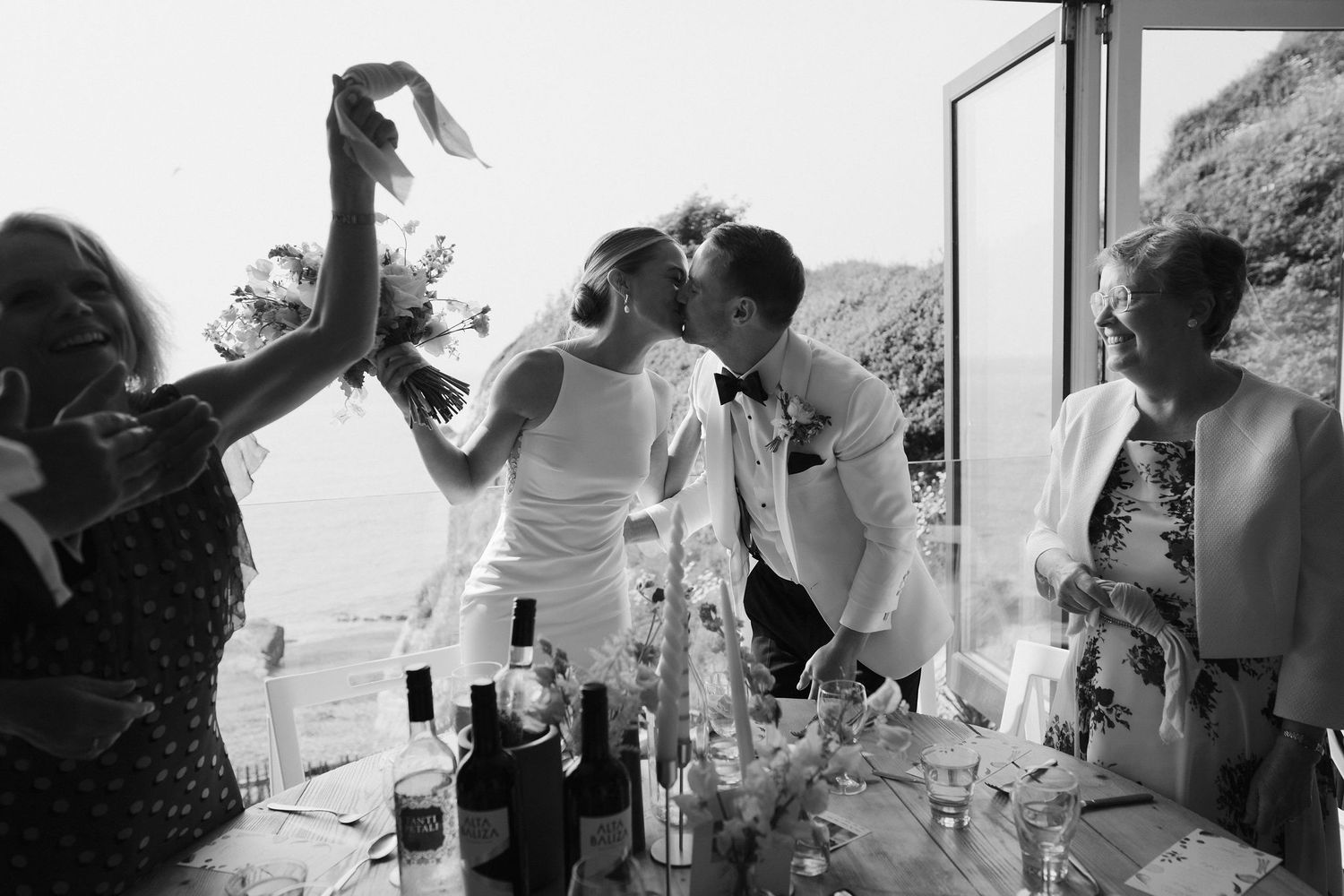 Wedding guests cheering Bride and grooms entrance to wedding breakfast at tunnels beach wedding venue in north devon