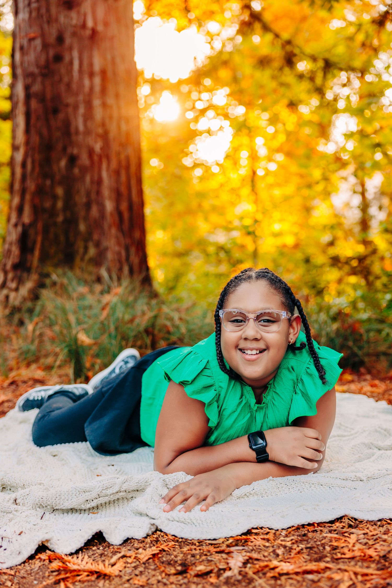 A series of playful poses on a white blanket surrounded by autumn trees and fallen leaves in golden light.