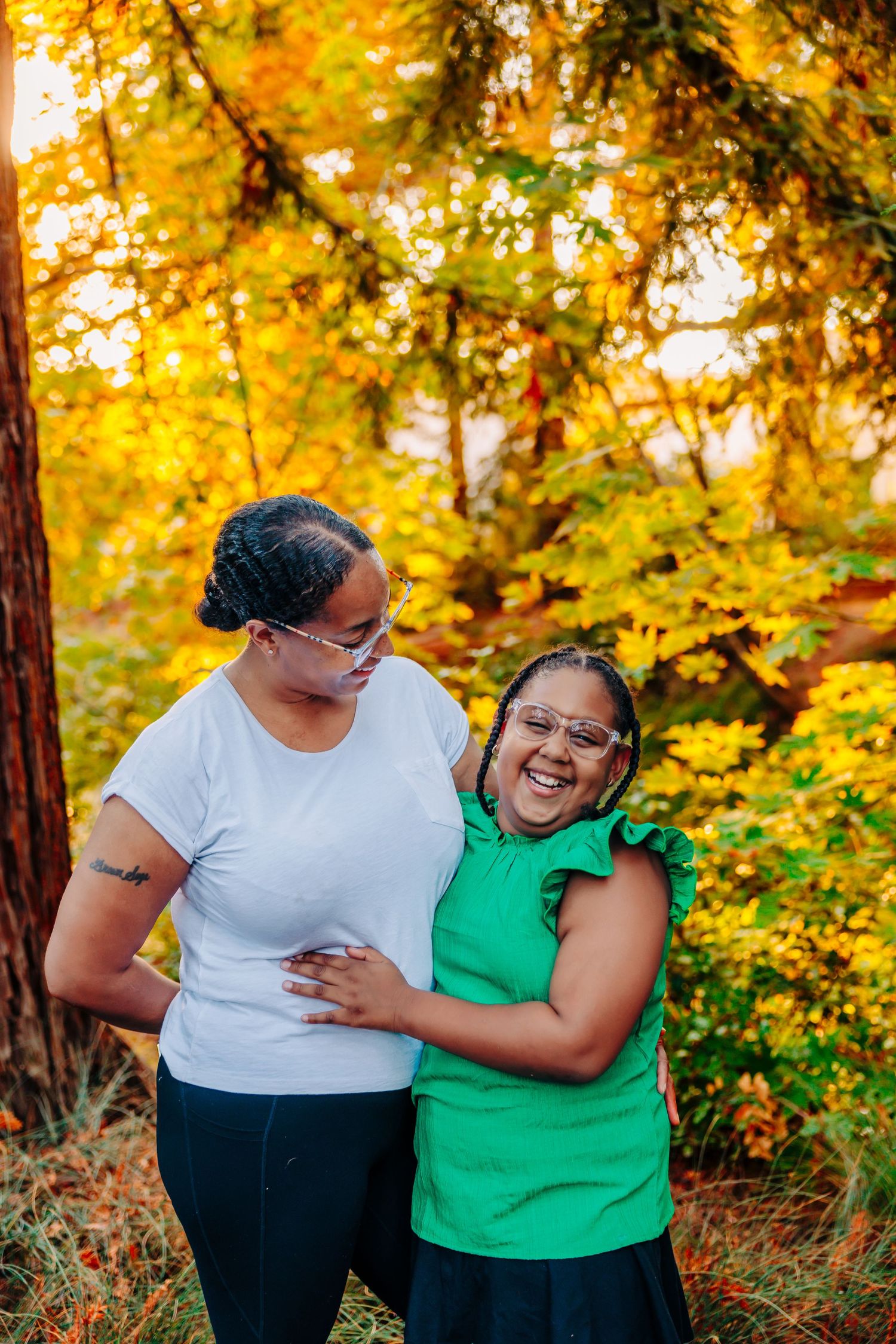 A couple shares a joyful moment together among golden autumn foliage in a park setting.