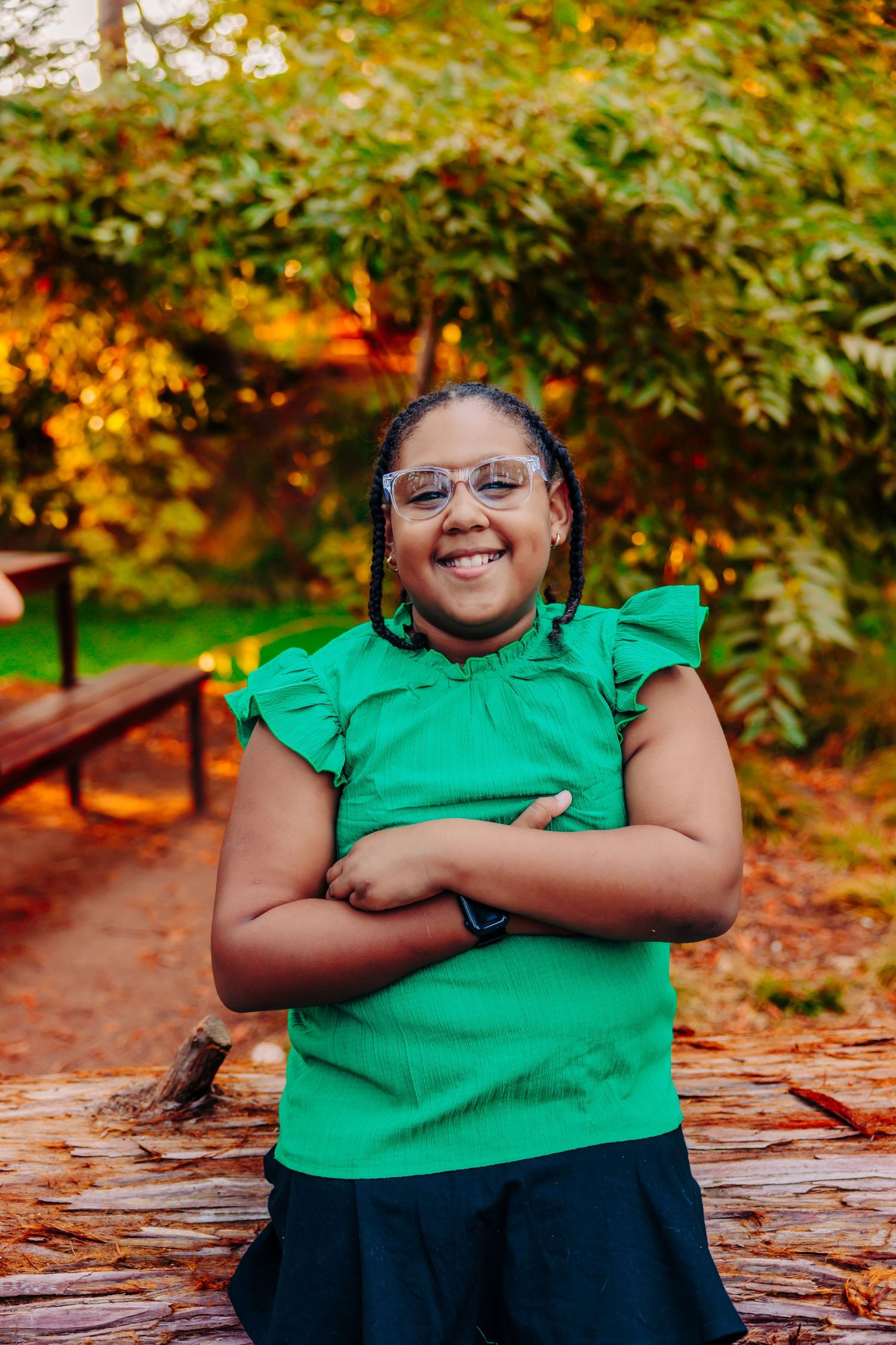 A joyful outdoor portrait session on a fallen log surrounded by vibrant fall colors and greenery.