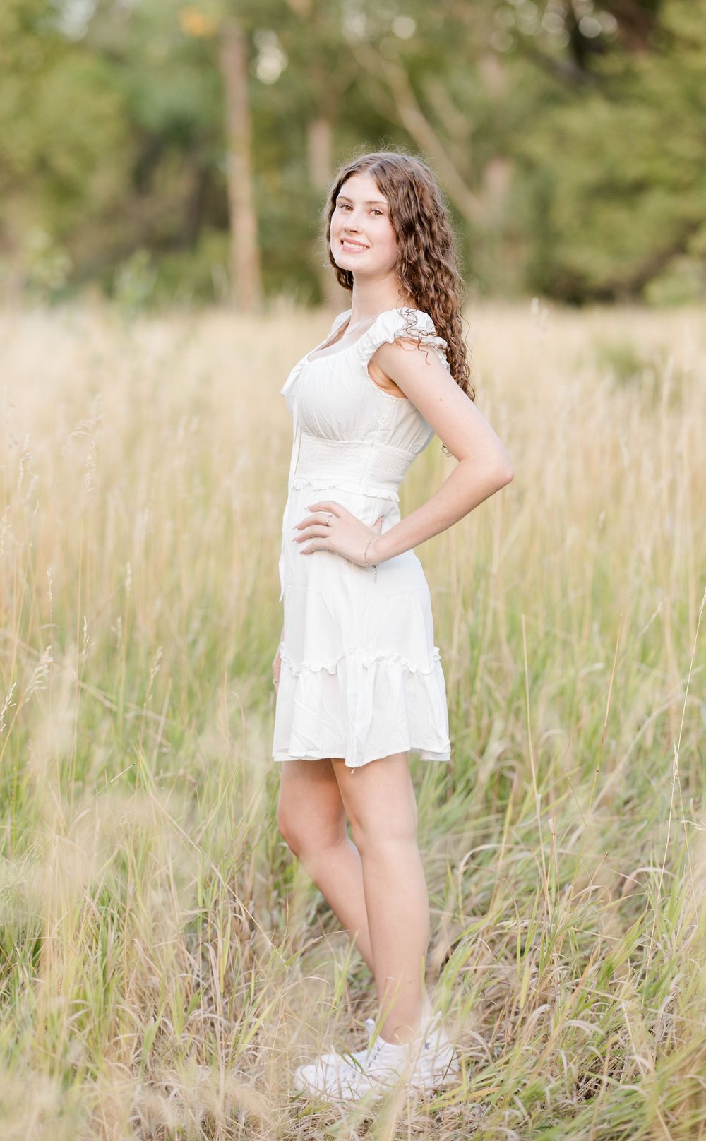 Series of portraits showing someone in a white dress twirling and posing in a sunlit meadow with tall grass.