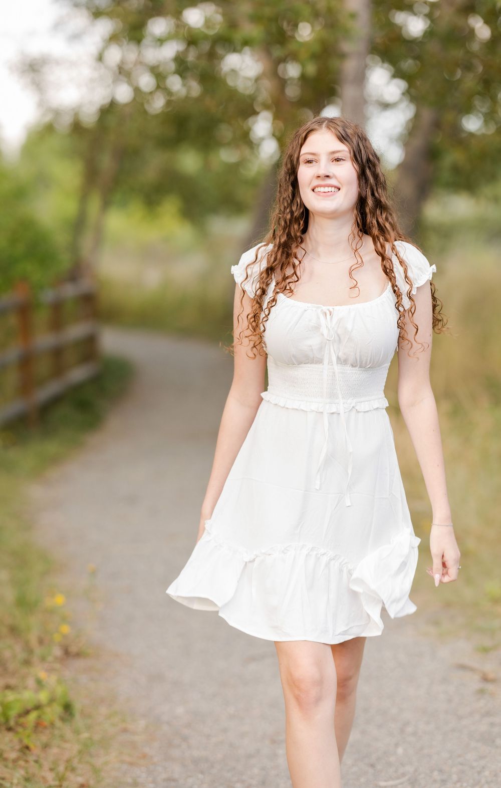 Candid outdoor photoshoot on path showing movement in flowing white dress.
