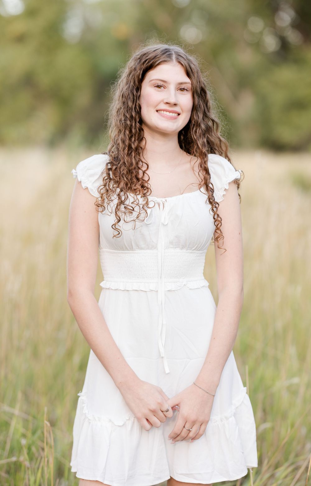 A series of outdoor portraits showing someone in a white dress sitting in a sunlit meadow with tall grass.