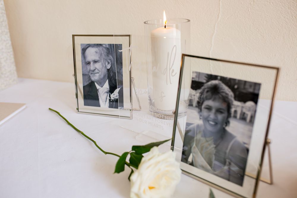 Black and white framed photographs displayed with white roses and candles.