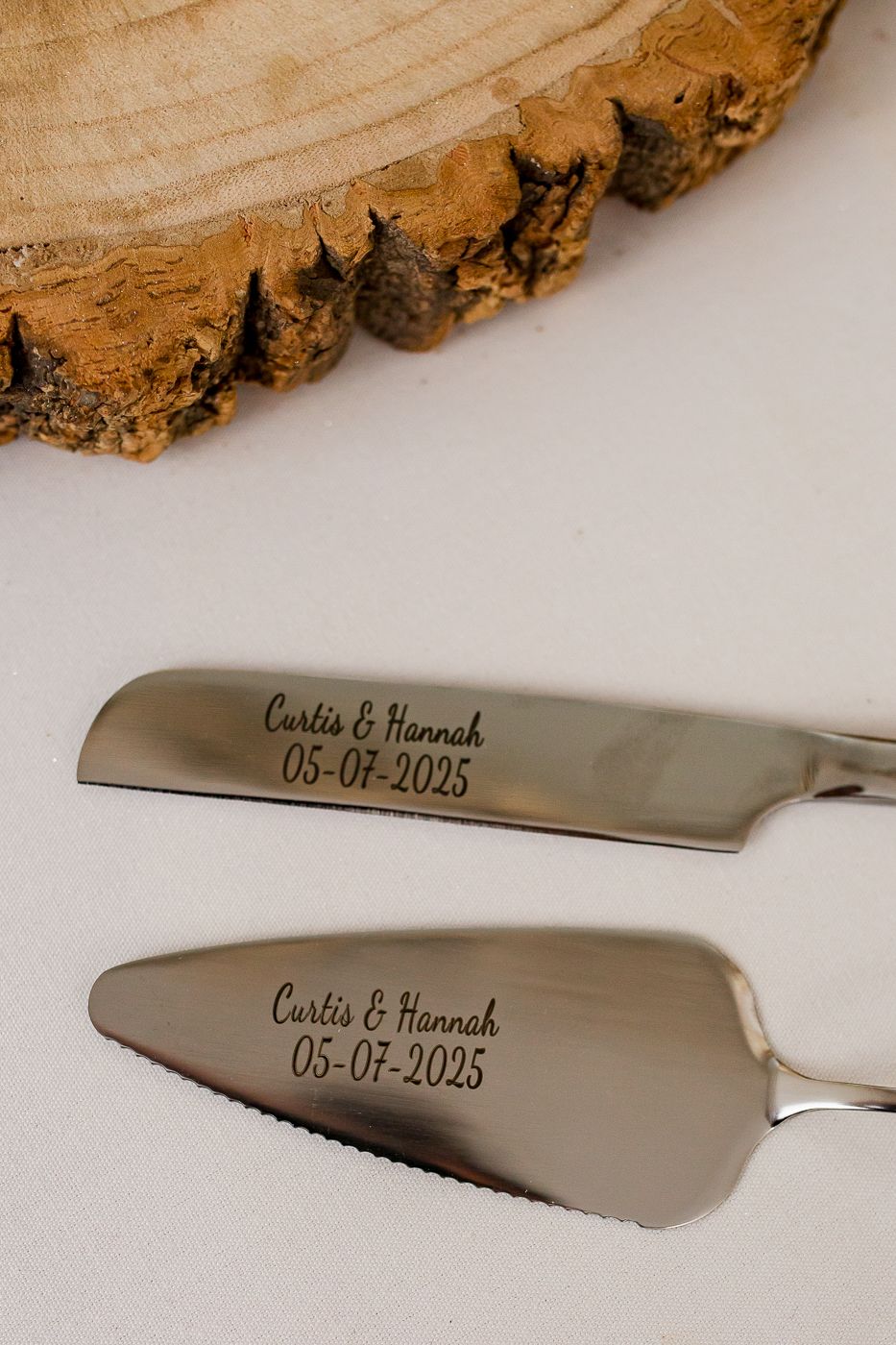Engraved wedding cake serving knife with date and names displayed on wooden surface.