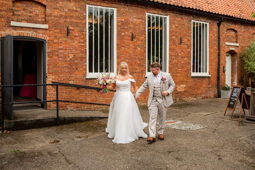 Outdoor wedding photos taken against historic red brick building exterior.