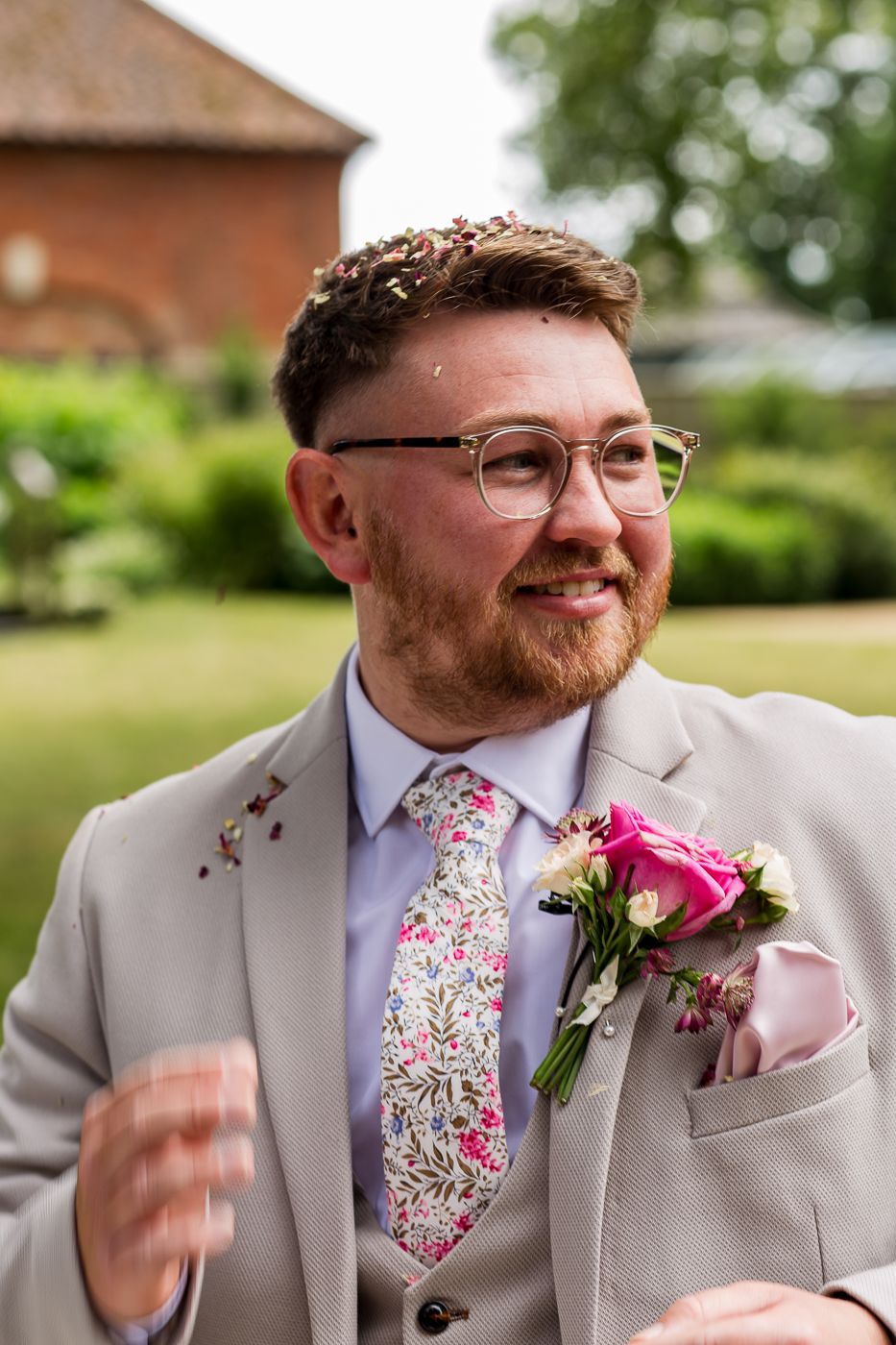 Wedding attire features a light gray suit with floral pink tie and boutonniere.