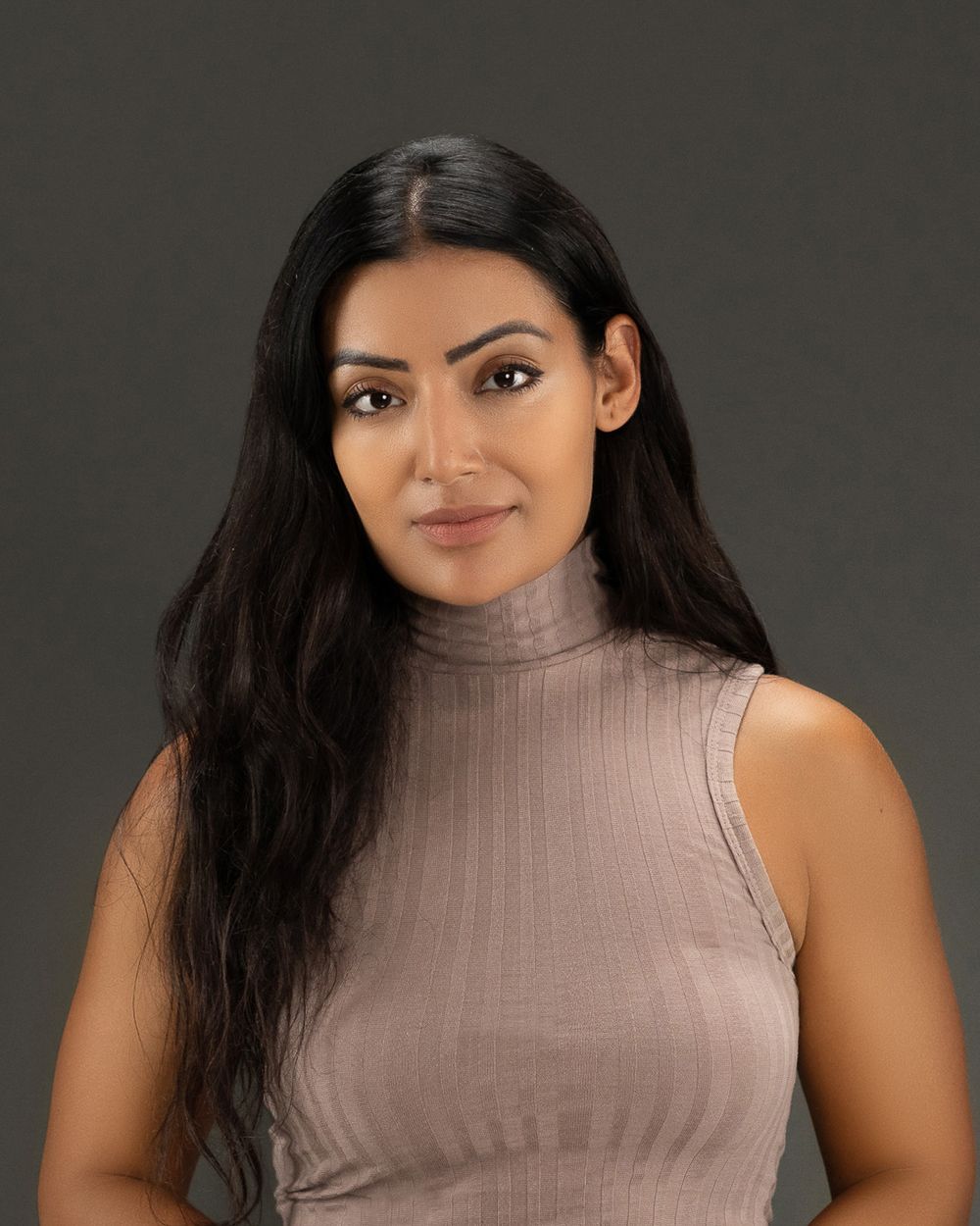 Woman in a sleeveless turtleneck top poses against a dark background in a collage of four similar photos.
