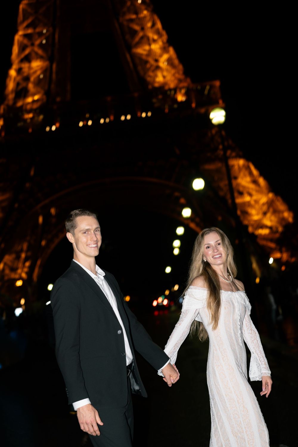 A couple in formal attire walks together at night in Paris. Editorial Paris photography.