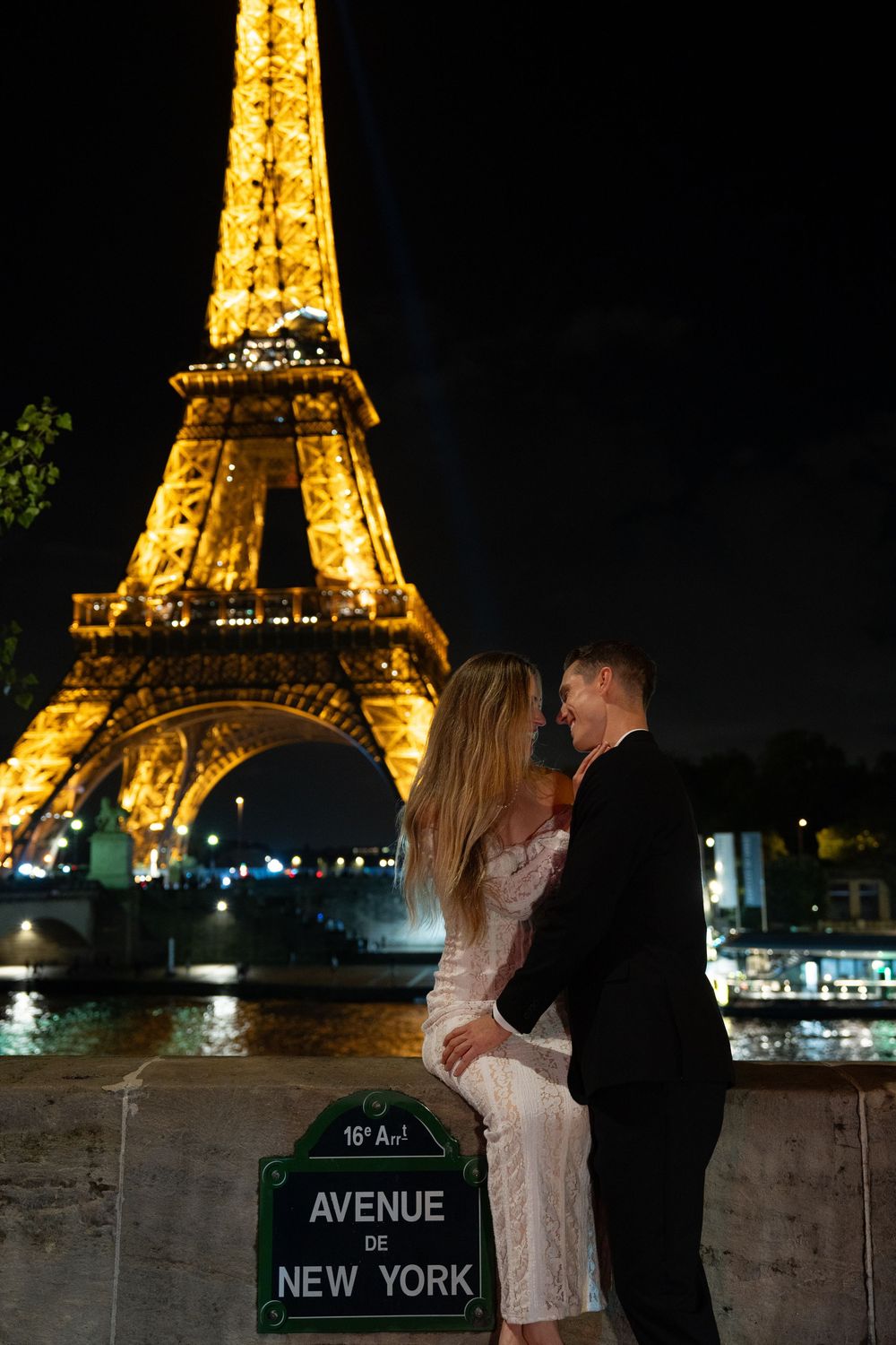 A romantic nighttime scene at the illuminated Eiffel Tower with Avenue New York street sign in Paris. Paris film photographer.