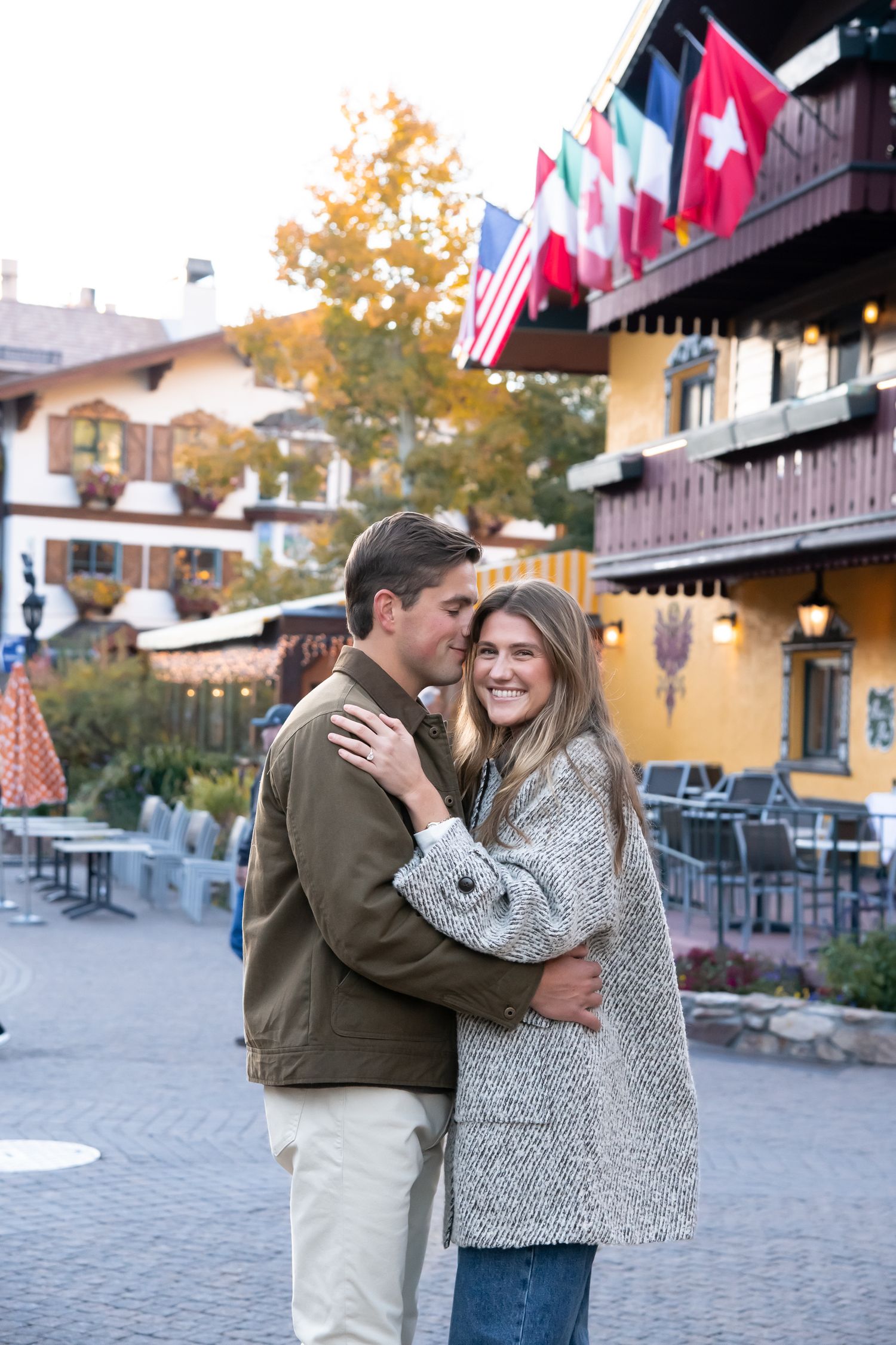 Sunset engagement photo of a couple in Vail Village Colorado with the cute buildings around them.