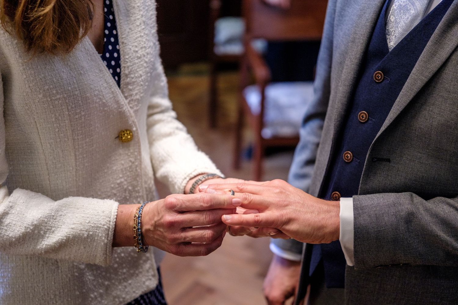 Close-up view of hands exchanging wedding rings during a traditional ceremony.