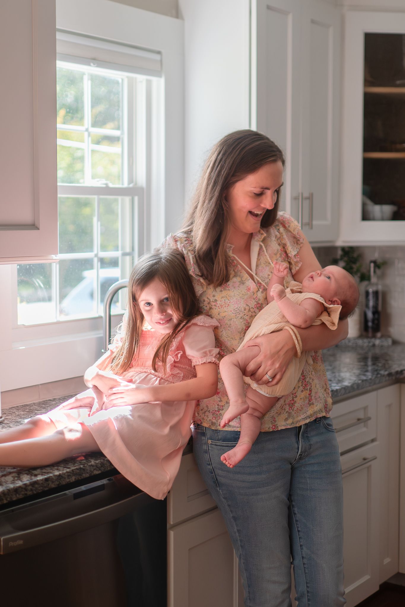 A series of four candid moments showing a parent and baby interacting in a sunlit kitchen by the window.