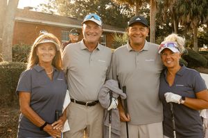 Golf tournament participants posing together in casual attire on the course.