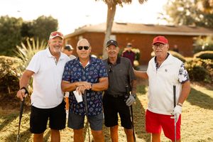 Group of people posing together on a sunny golf course during a casual outdoor gathering.