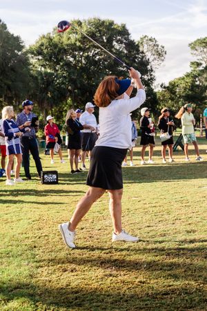 Group of golfers practicing their swings together on a grassy field during an outdoor training session.