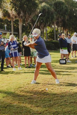 Multiple golfers practicing their swings in a group lesson on a sunny golf course.