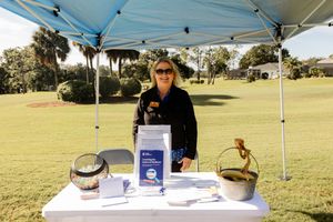 Vendor booth with display table under blue canopy tent on golf course.