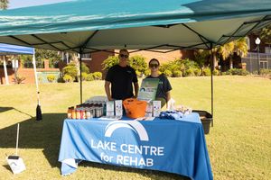Blue branded event tables set up outdoors with promotional materials and banners.