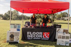 Floor & Decor promotional booth setup with red tent at outdoor golf event.