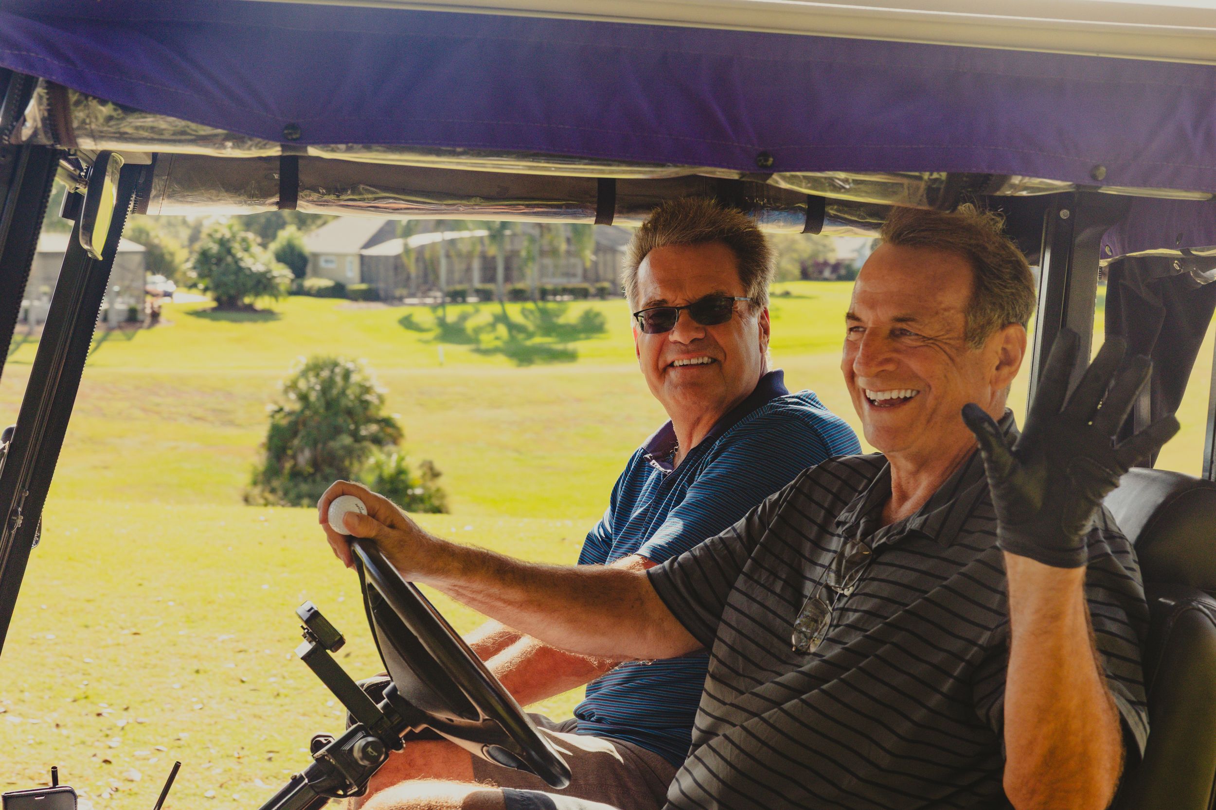 Group of people riding in golf carts on a sunny day at a golf course.