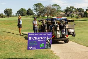 Golf carts and participants gathered on a sunny golf course with event banners visible.
