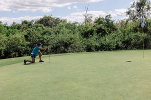 Scenic view of an empty golf course with rolling green hills and trees under blue skies.