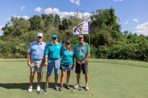 Golfers posing together on a lush green golf course under blue skies.