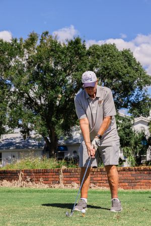 Golfer practicing their swing form on a well-maintained golf course under blue skies.