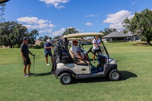 Golf carts parked on a lush green course under blue skies during a tournament.