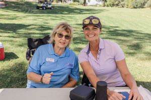 Golfers relaxing and socializing in the shade during a charity tournament event.