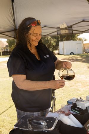 Person under tent canopy organizing materials and supplies at an outdoor event.