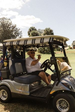 Golf carts lined up on a sunny day at a golf course with players ready for a round.